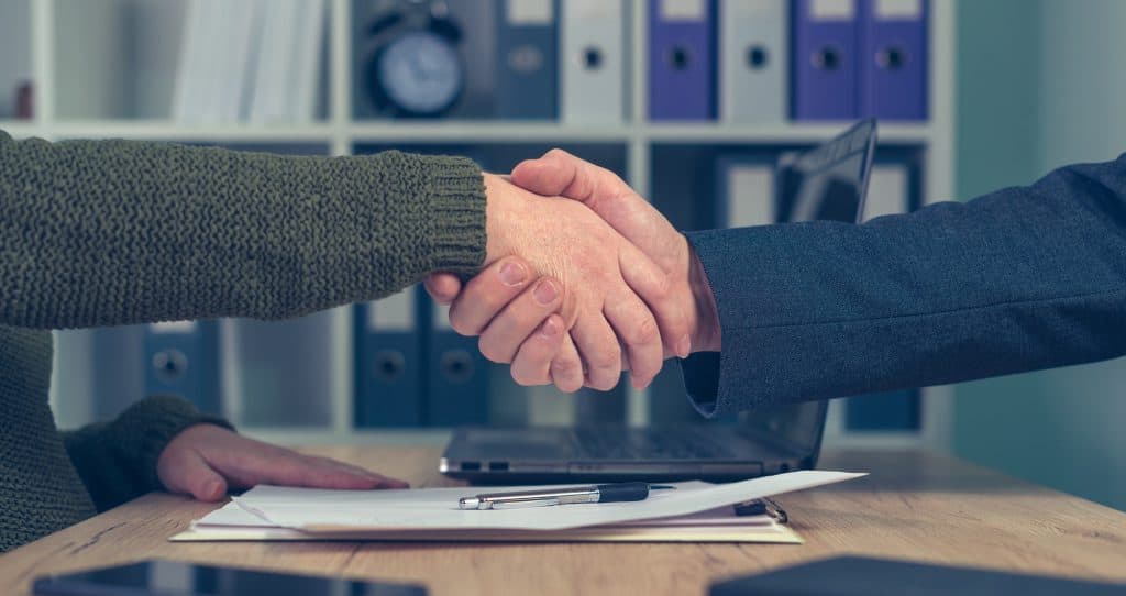 Hombre y mujer dándose la mano sobre un acuerdo comercial