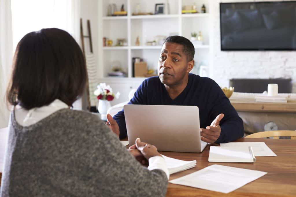 Homem milenar com computador portátil dando conselhos financeiros a uma mulher